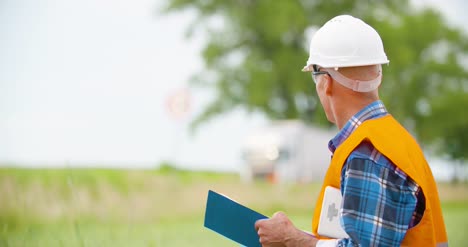 Engineer-Analyzing-Traffic-Polution-On-Clipboard-Amidst-Crops-At-Farm-8