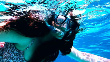 woman snorkeling in zanzibar with googles between tropical fishes around