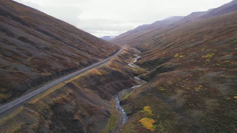 aerial: revelación inversa de un suv blanco en la carretera de circunvalación de islandia, que es una carretera panorámica a través de una pintoresca zona remota del fiordo que conduce a la niebla y la neblina en la distancia