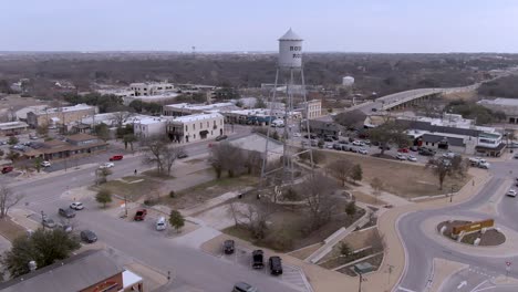 Panorámica-Aérea-Hasta-Revelar-Y-Volar-Por-La-Torre-De-Agua-Plateada-En-El-Centro-De-Round-Rock,-Texas