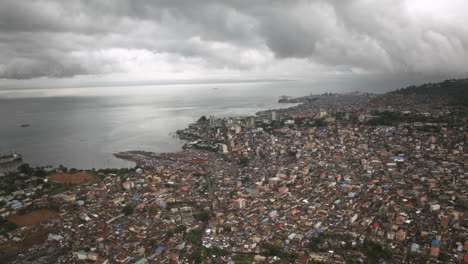 Aerial-hyperlapse-of-the-downtown-of-Freetown,-Sierra-Leone-with-storm-clouds-in-the-background