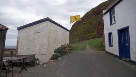 Flag-shot-with-engraved-lion-waving-in-Little-Town-a-small-seaside-town-in-Aberdeenshire,-Scotland,-UK