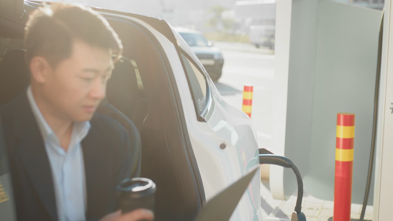 사업가 가 노트북 에서 일 하면서 에브 를 충전 하고 있다
