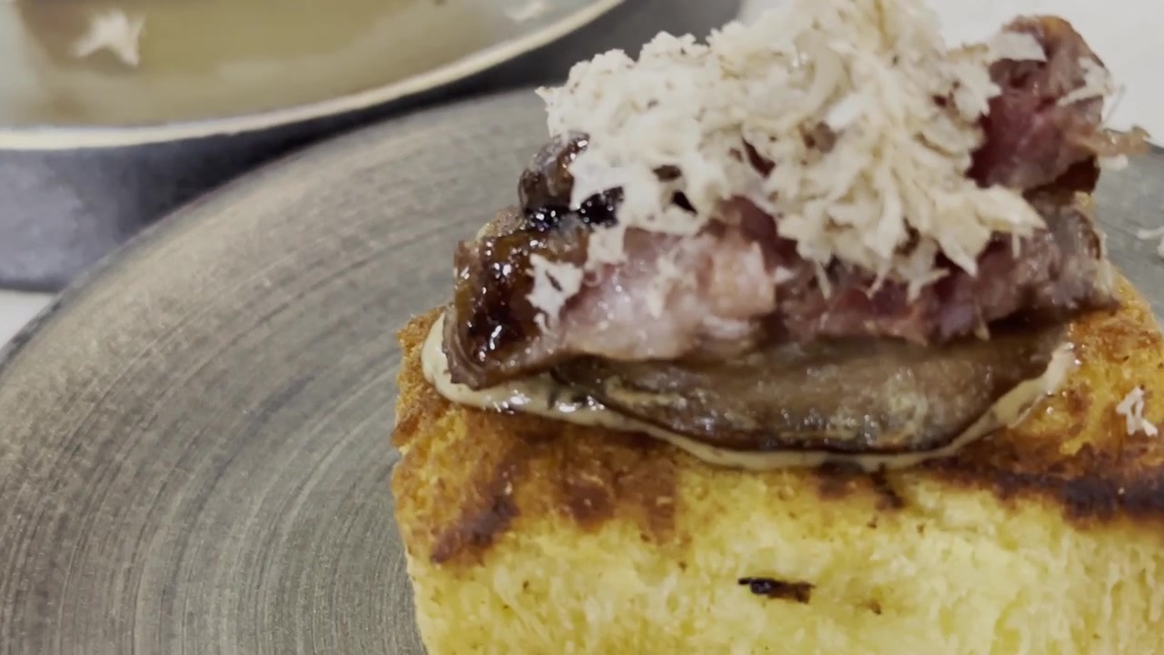 Primo piano di foie gras scottato in padella servito su pane tostato e guarnito con scaglie di tartufo nero, presentato come un lussuoso antipasto gourmet.