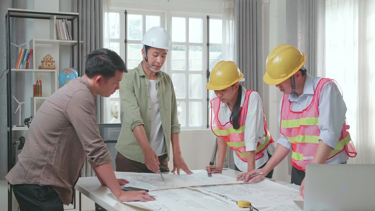 Three Asian Engineers With Helmets Presenting Work To A Man At The Office