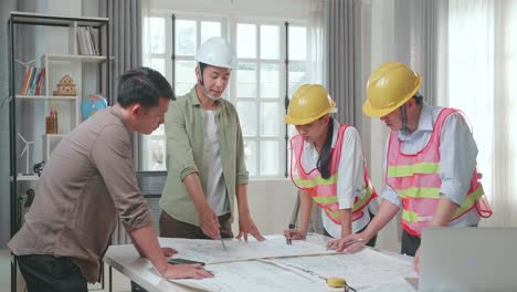 three asian engineers with helmets presenting work to a man at the office