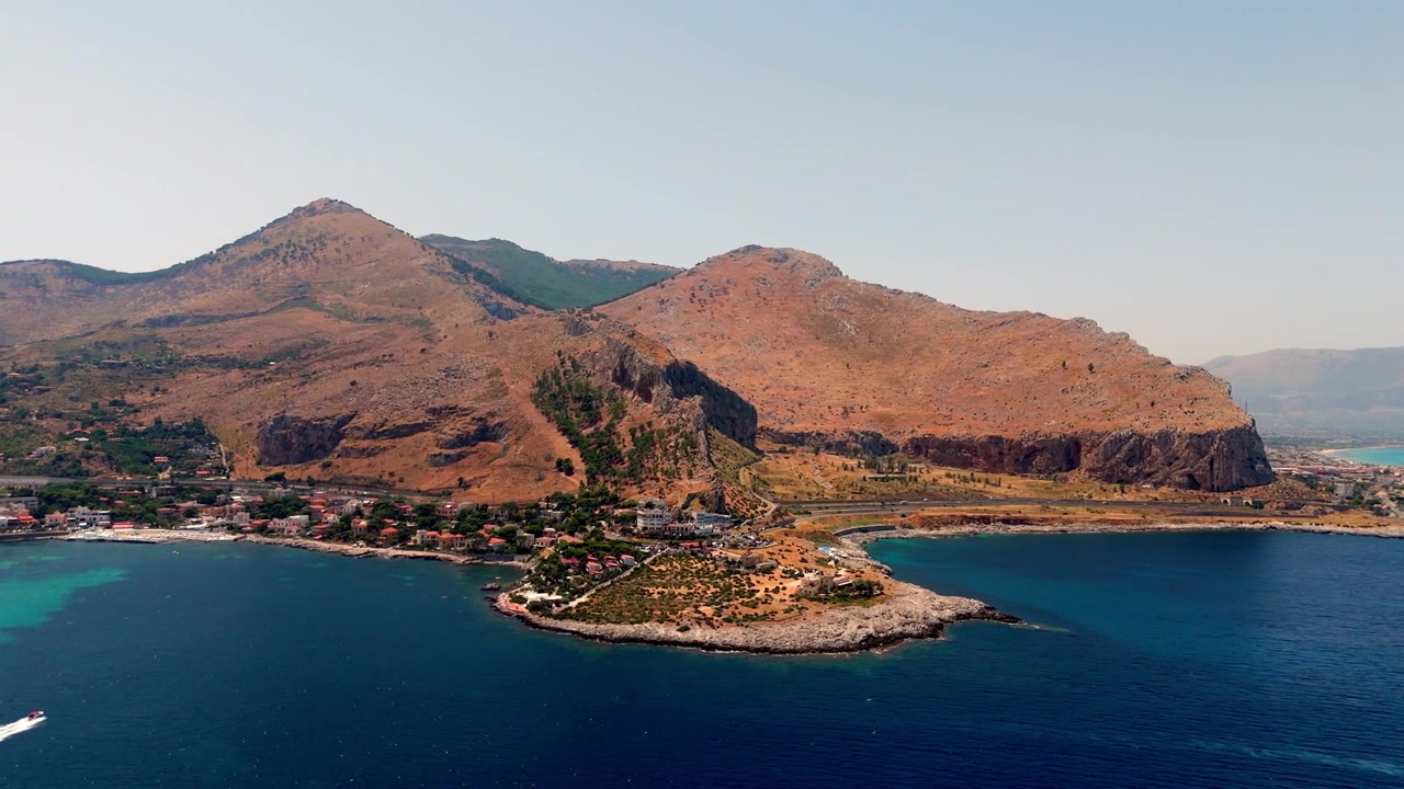 İtalya'nın Sicilya adasındaki Palermo'nun Sferracavallo bölgesinde, manzaralı burun, kıyı suları ve yerleşim yerinin gündüz havadan görünümü.