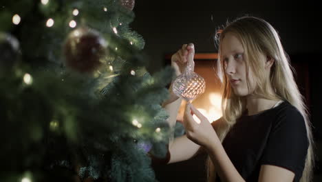 the child holds a beautiful christmas toy in his hands. sitting by a large christmas tree, a fire in the fireplace is burning in the background