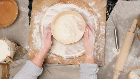 female hands sift white wheat flour through a wooden round sieve