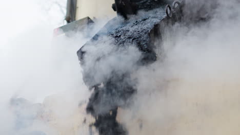 maquinaria de pavimentación pesada que deja caer bitumen de asfalto negro fresco y caliente en el suelo con humo - ángulo bajo