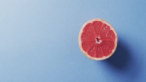 Video-of-sliced-red-grapefruit-with-copy-space-over-blue-background