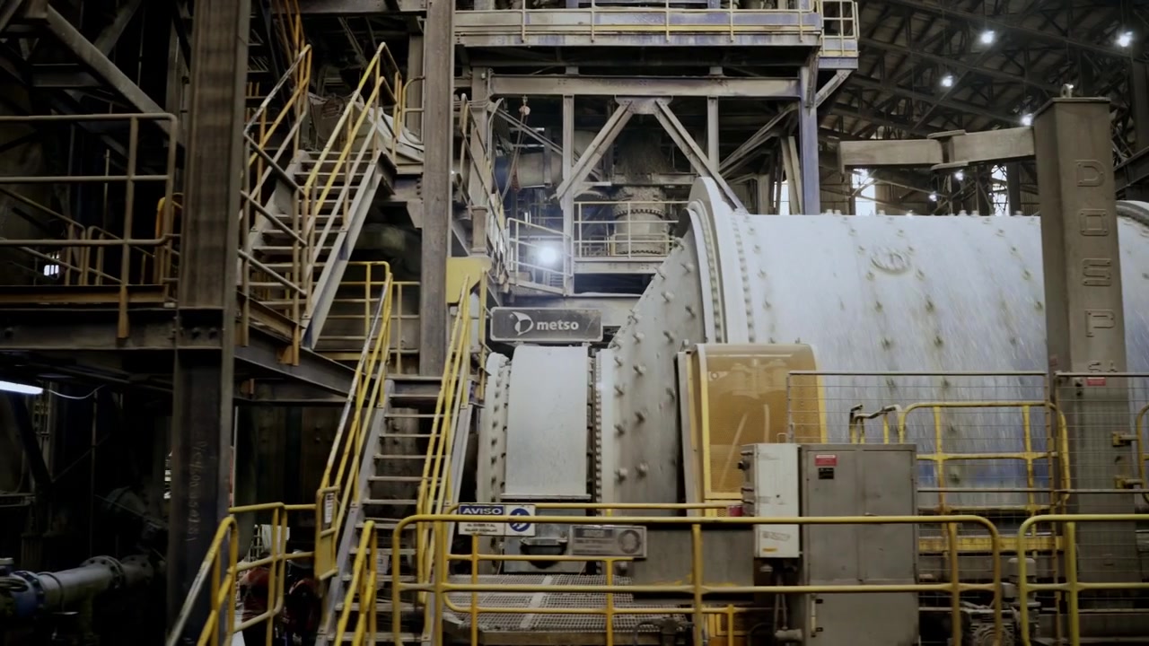 Slow left pan revealing an operating industrial grinding mill inside a copper processing facility at El Teniente Mine in Chile. Mining infrastructure and mineral processing equipment in operation.