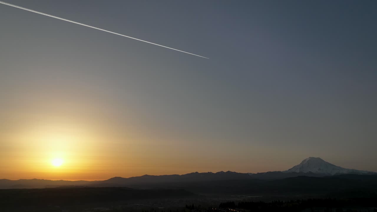 Epic shot of a jet flying between the sunrise and Mount Rainier in Washington state.