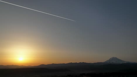 epic shot of a jet flying between the sunrise and mount rainier in washington state.