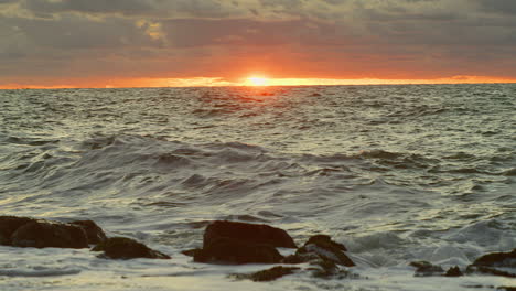 northsea waves hitting a dyke at sunset