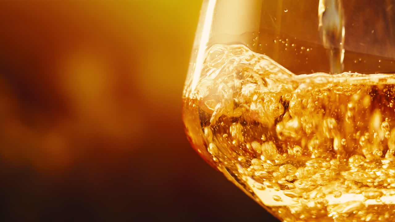 Orange or white wine bottle and glass against a sunset in a peaceful vineyard, pouring of ecological natural wine.