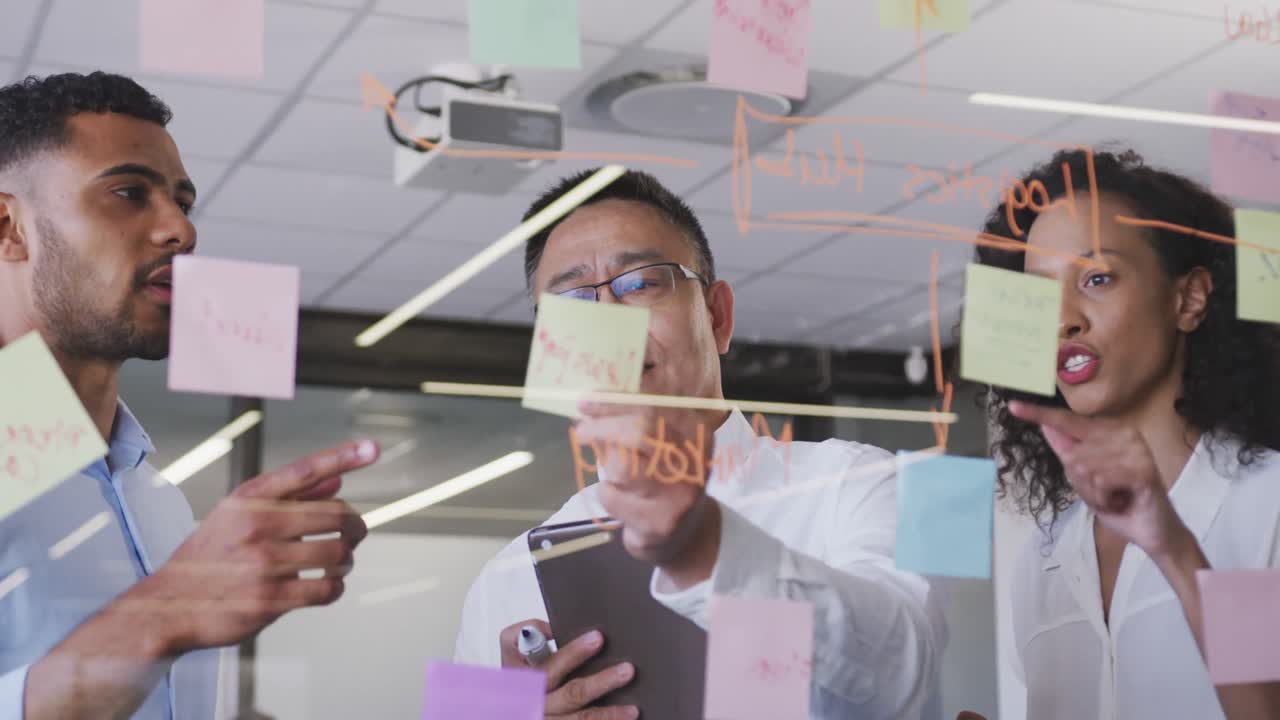 Senior businessman with digital tablet discussing with young business people over memo notes