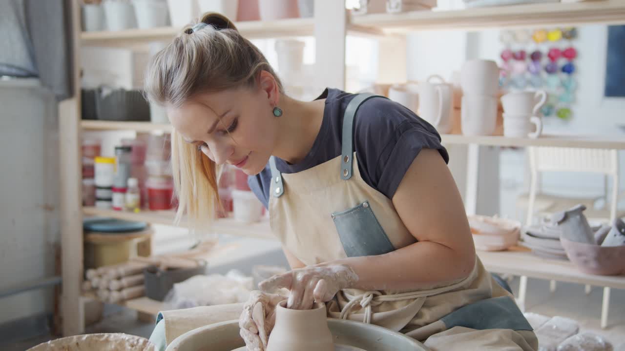 Female potter makes a pot on the pottery wheel.