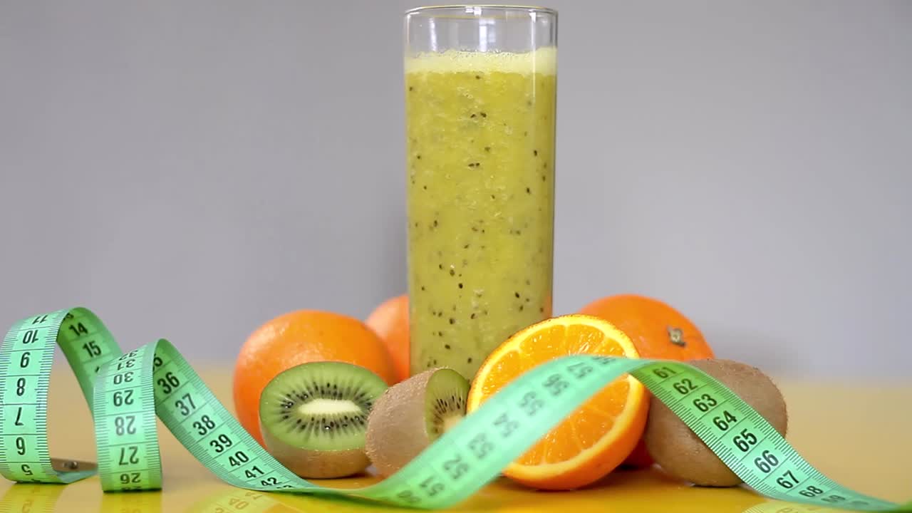 succo d'arancia appena spremuto e kiwi in un bicchiere con metro a nastro su un tavolo video d'archivio filmati d'archivio