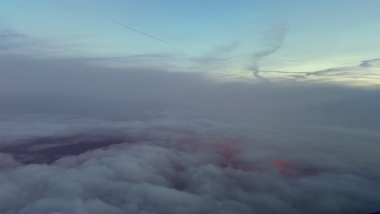 Cockpit view flying though ethereal clouds at sunrise, with a golden horizon light through the clouds