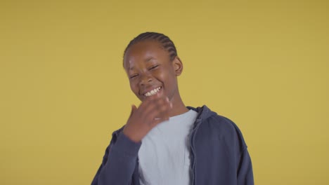 studio portrait of young boy smiling and laughing against yellow background 2