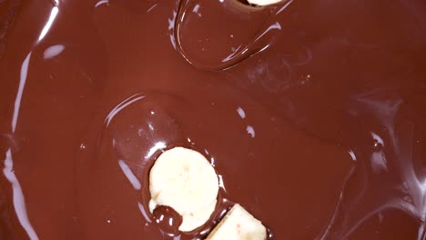 banana slices submerged in rich chocolate sauce