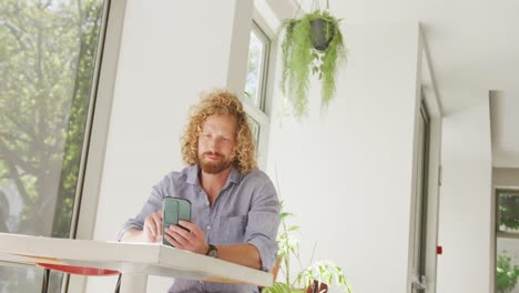 Hombre-Caucásico-Feliz-Usando-Un-Teléfono-Inteligente-Y-Sentado-A-La-Mesa-En-Un-Café