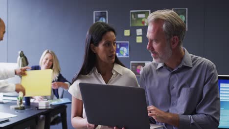 diversas personas de negocios que usan computadoras portátiles hablando en la oficina y colegas trabajando detrás