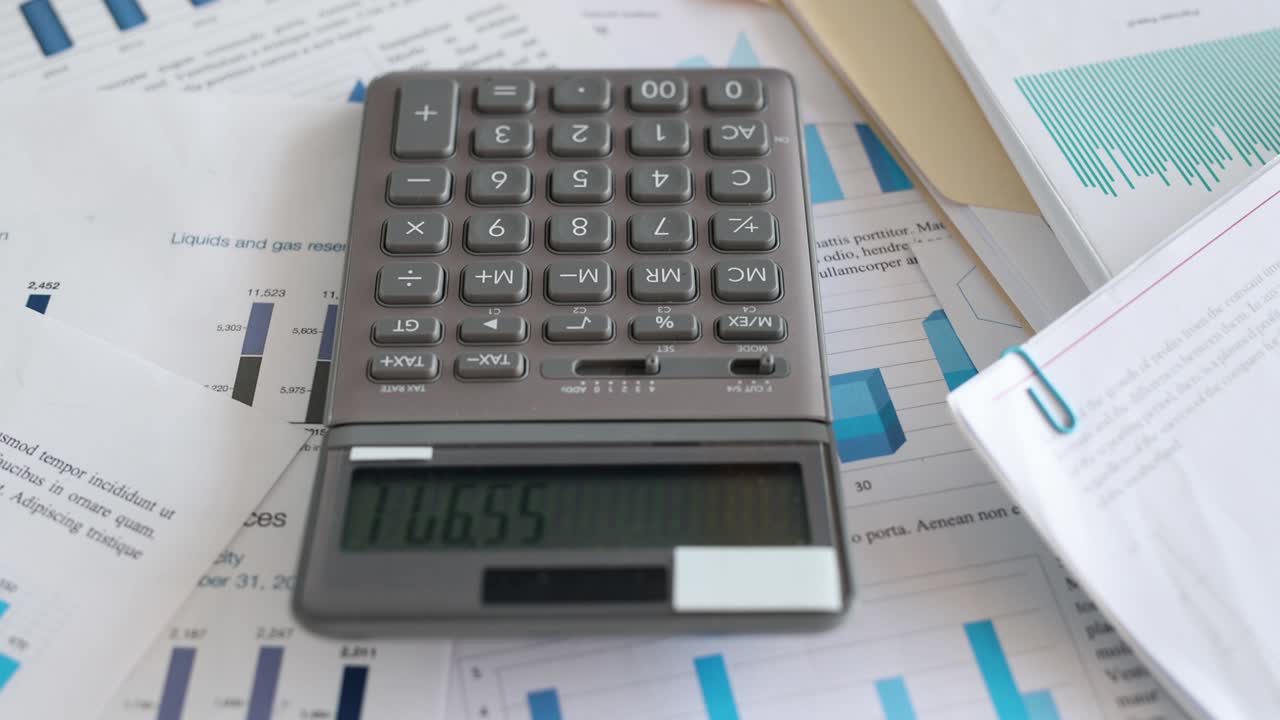 calculadora que se encuentra en documentos con gráficos en la oficina 4k película en cámara lenta