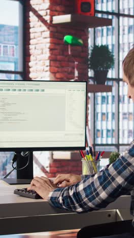 vertical video man in home office looking at green screen tablet and computer, typing code
