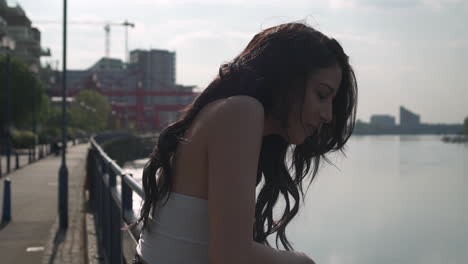 beautiful latina woman on holiday leaning against the railing, looking at the river thames in london, thinking, smiling and wandering