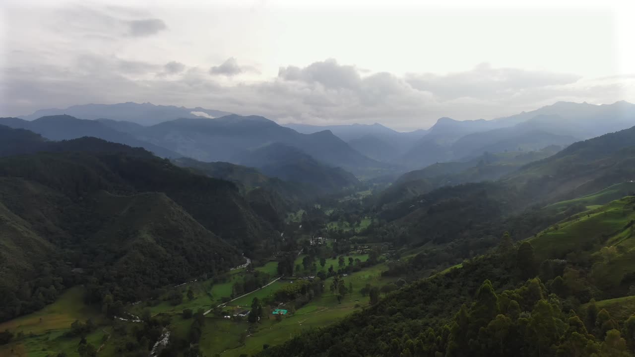 Lenta ascesa sopra una valle verde tra montagne azzurre