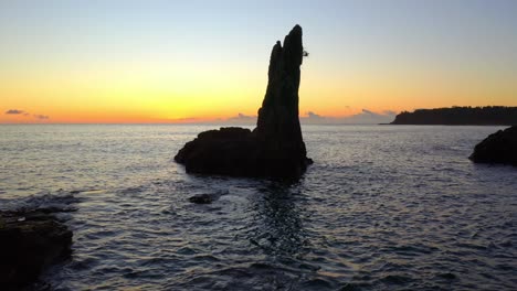 silhouetted rock formations of cathedral rocks against orange sunset sky in pacific ocean of new south wales, australia