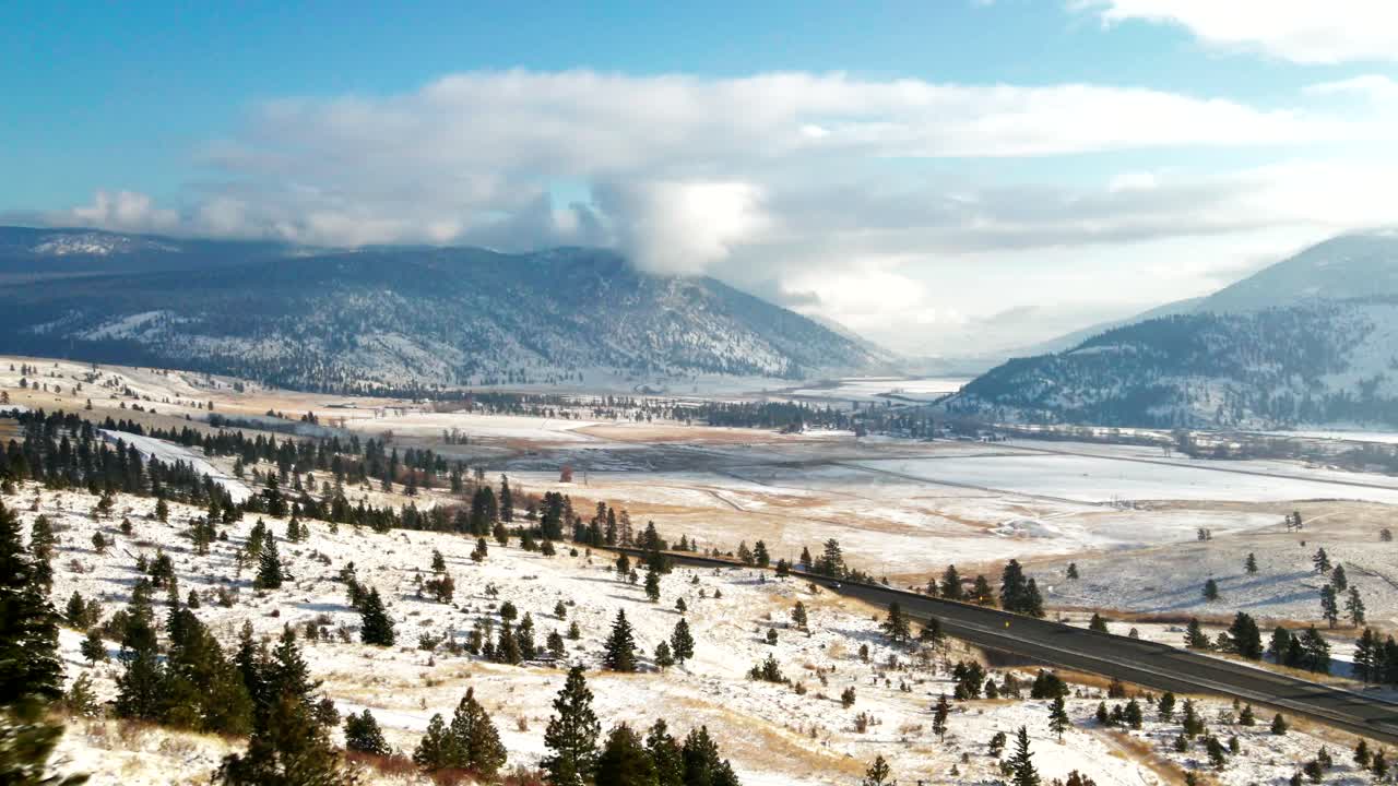 escena cinematográfica de la autopista 5a rodeada de árboles, montañas de pastizales del valle de nicola en invierno, paisaje cubierto de nieve con sol cerca de merritt, bc canada