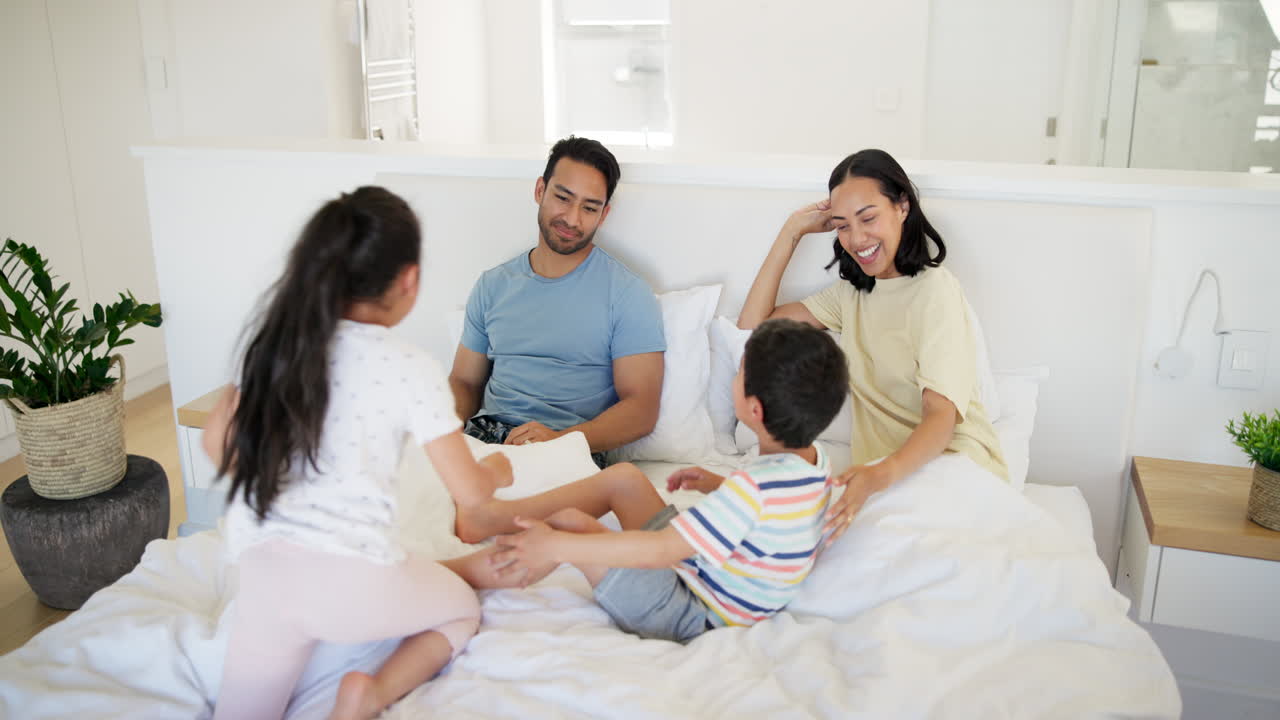 행복한 가족이 침대에서 놀고 있습니다.