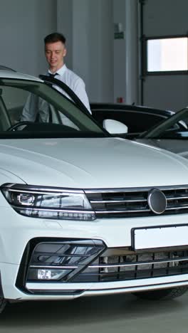 car salesperson showing car to customer in showroom