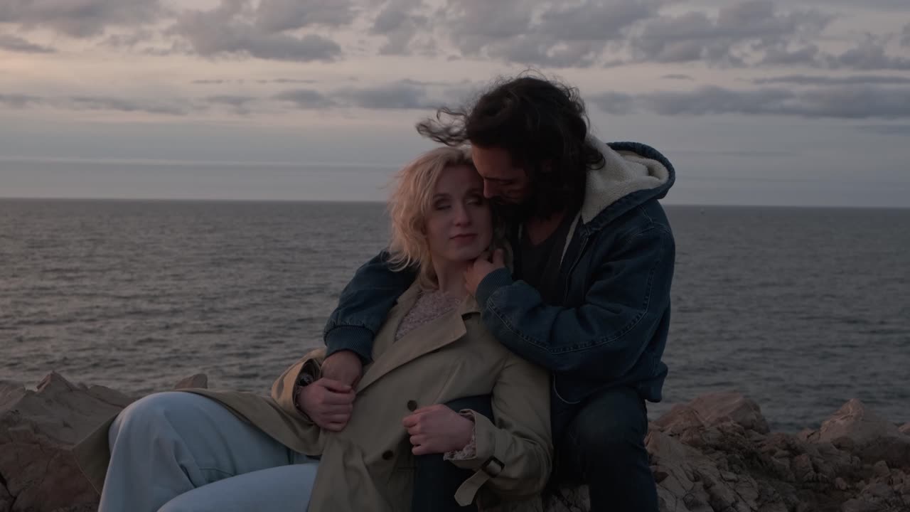 pareja descansando en la costa rocosa