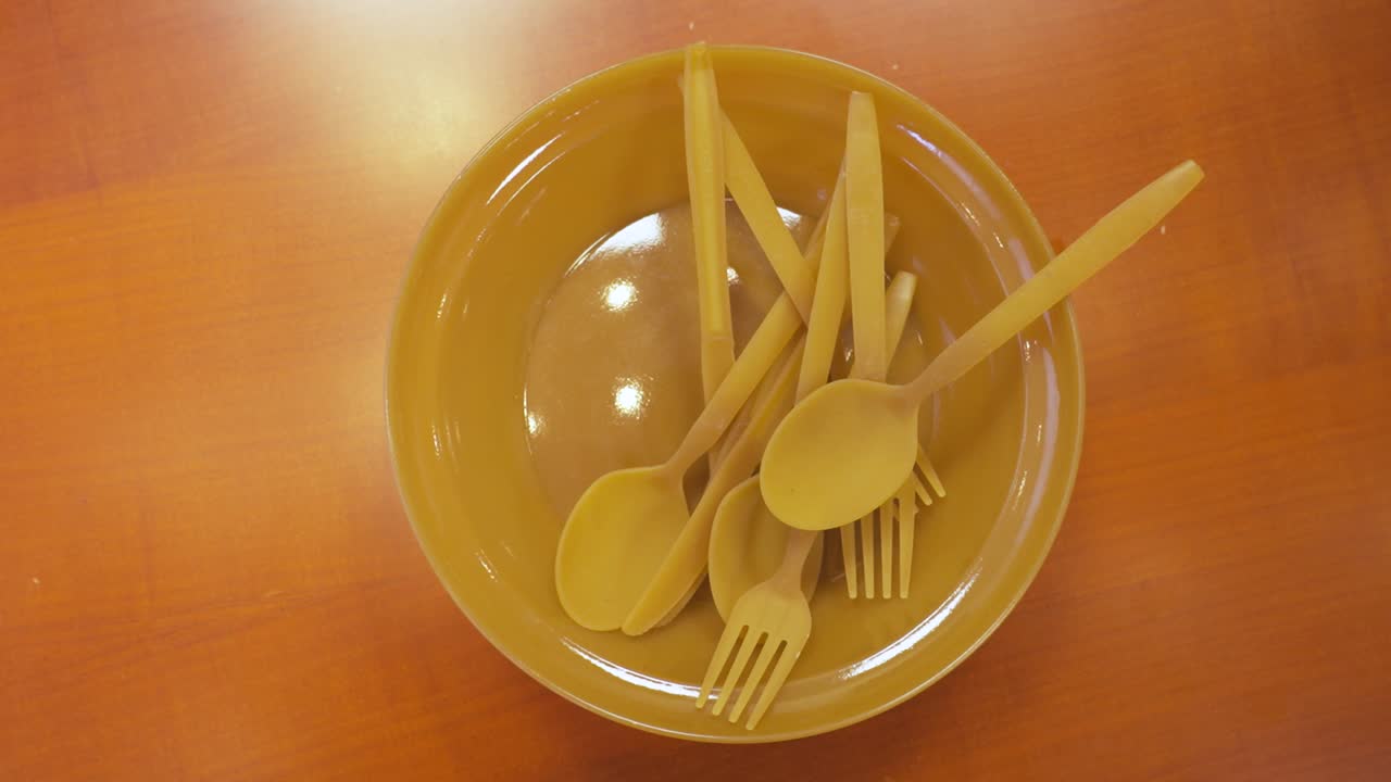 cubiertos amarillos ecológicos en un cuenco sobre una mesa de madera