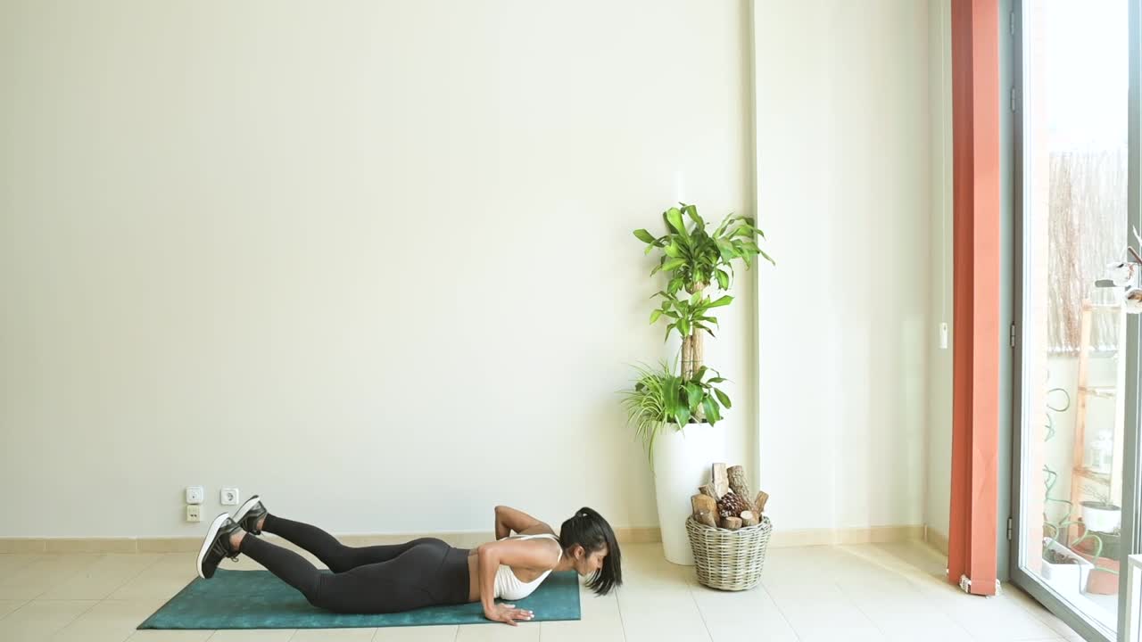 deportista étnica saltando durante el entrenamiento en la habitación