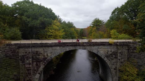 El-Joven-Se-Sienta-En-Un-Camino-De-Grava-En-Un-Puente-Sobre-Un-Río-En-Otoño