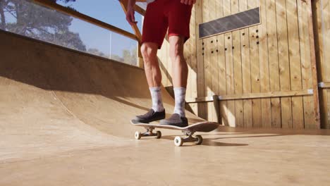 Video-of-low-section-of-caucasian-male-skateboarder-training-in-skate-park