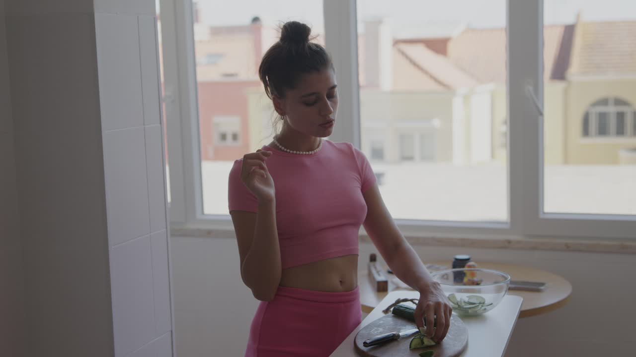 Woman preparing cucumber salad in kitchen