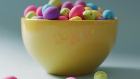 Close-up-bowl-with-colorful-easter-eggs-on-green-background