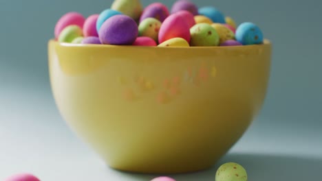 close up bowl with colorful easter eggs on green background