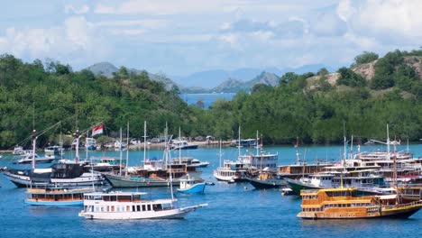 Liveaboard,-fishing-and-tour-boats-docked-in-fishing-village-of-Labuan-Bajo-on-Flores-island,-Nusa-Tenggara-region-of-east-Indonesia,-with-stunning-view-of-islands-in-the-distance