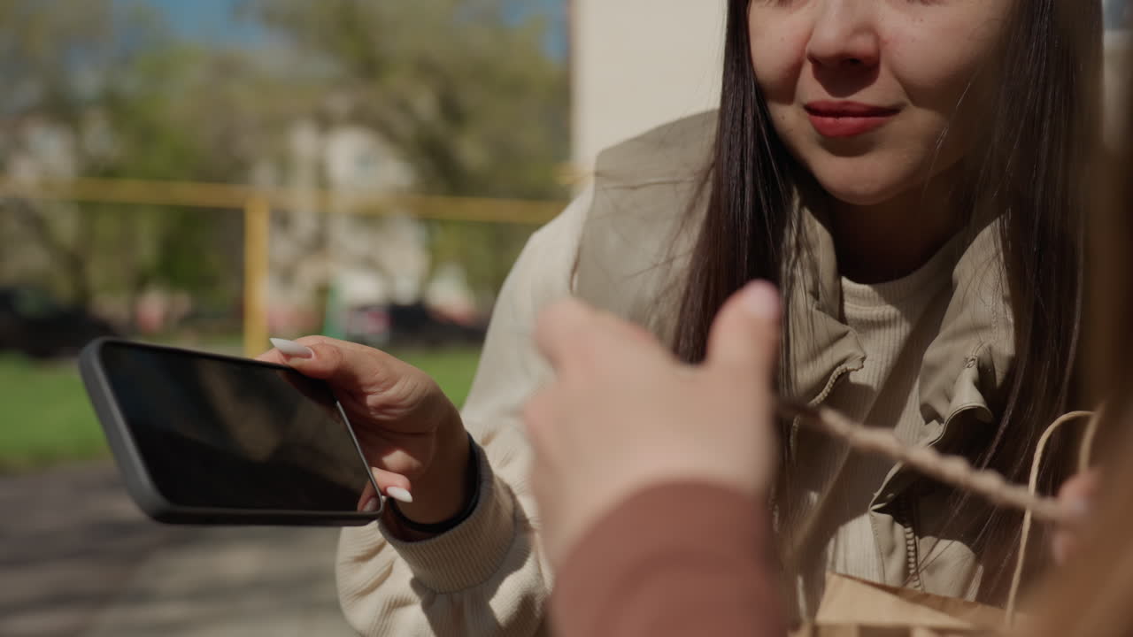 Женщина помогает молодой подруге на открытом воздухе; добрая дама обучает юную спутницу творческим проектам на природе; женщина, проявляя заботу, любезно наставляет молодую подругу в занятиях рукоделием на открытом воздухе.