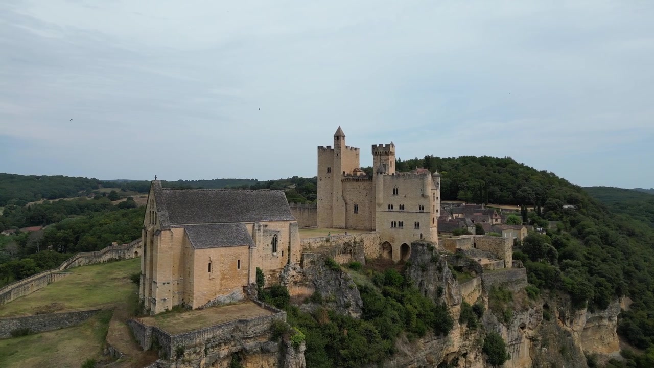 Veduta aerea con drone nella campagna francese di una piccola e antica città medievale in cima a una montagna, circondata da una foresta verde, con un castello a Beynac et Cazenac