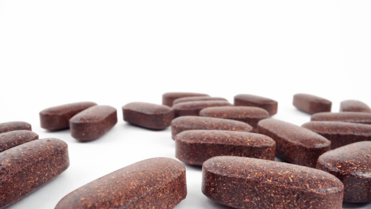 Various herbal brown tablets on a white surface with selective focus