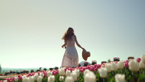 Happy-girl-turning-around-in-tulips-garden.Creative-young-woman-enjoying-flowers
