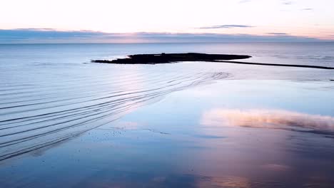 Malerische-Drohnenaufnahme-Der-Ruhigen-Meereswellen,-Die-Bei-Sonnenaufgang-Den-Sand-Am-Skerries-Beach-Hochrollen,-Republik-Irland